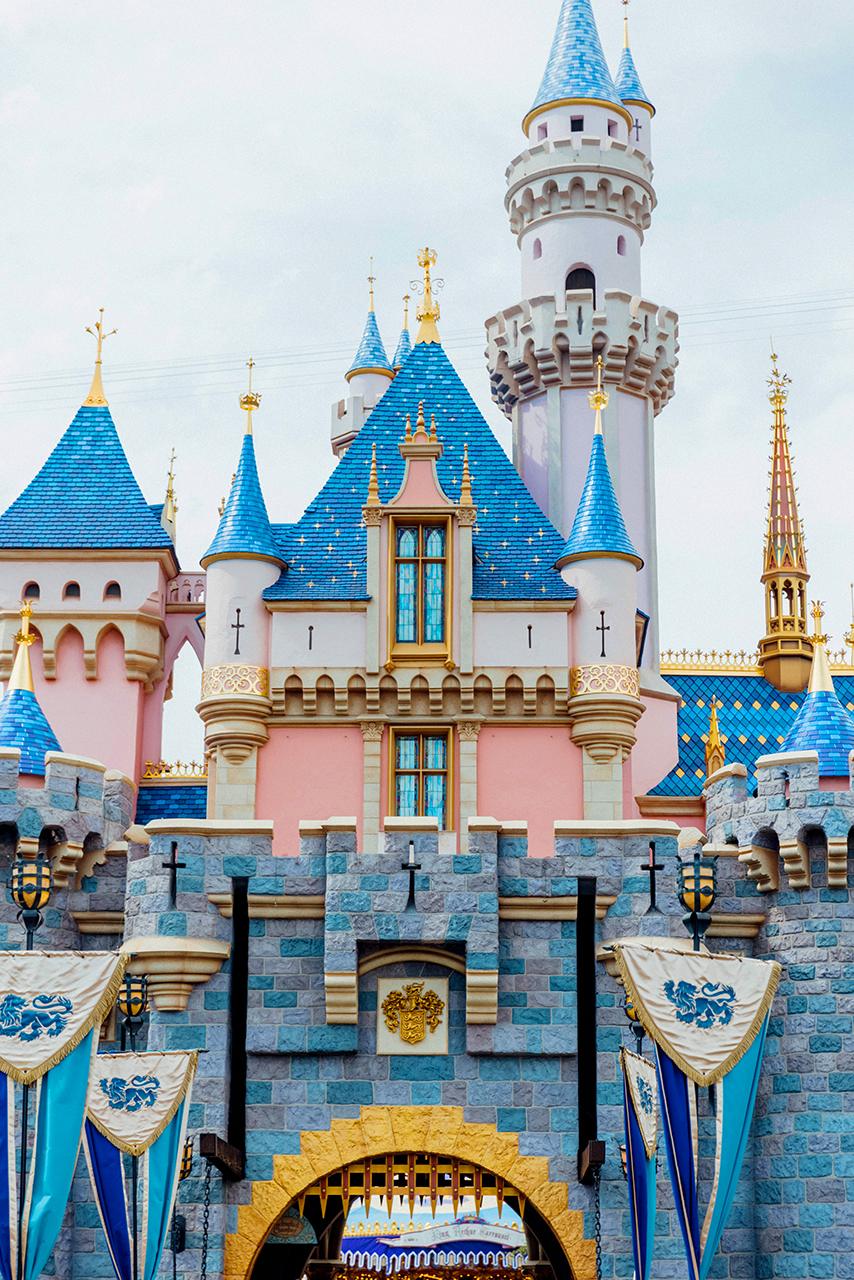 Fairy-tale castle with golden spires, pink walls, and blue turrets against cloudy sky