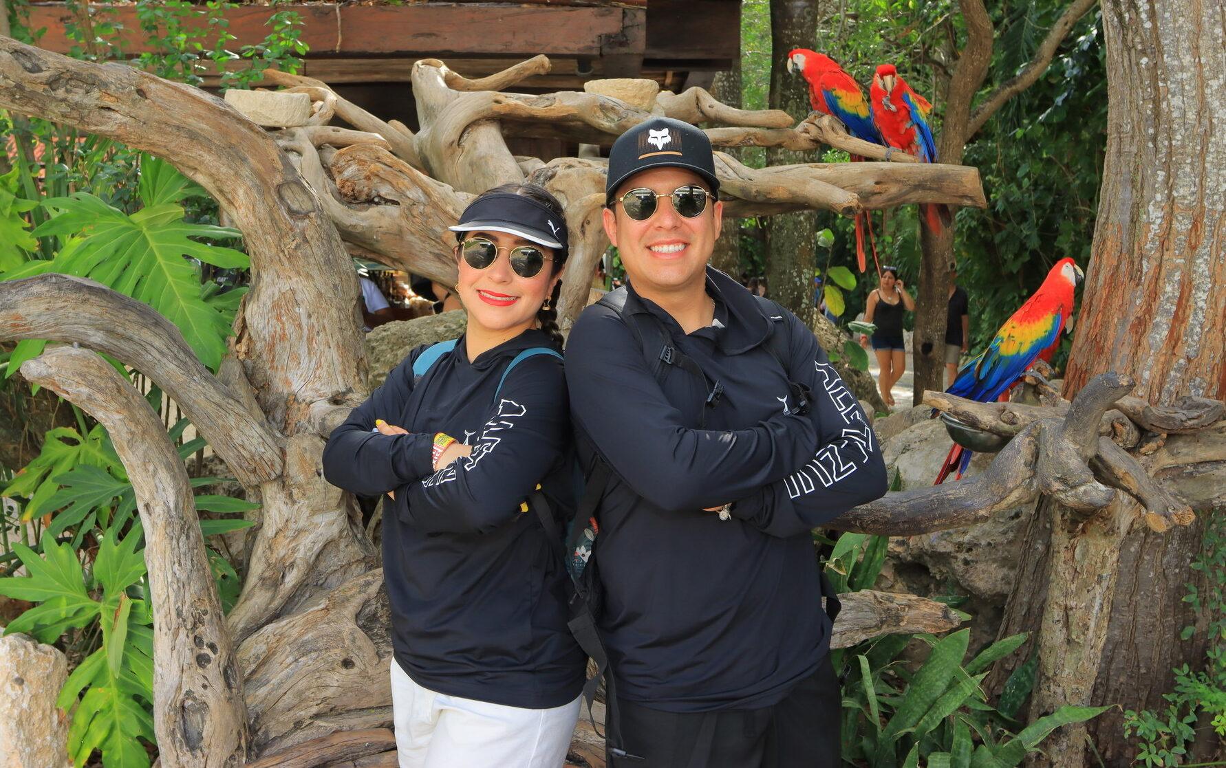 Friends posing with parrots in lush tropical jungle setting