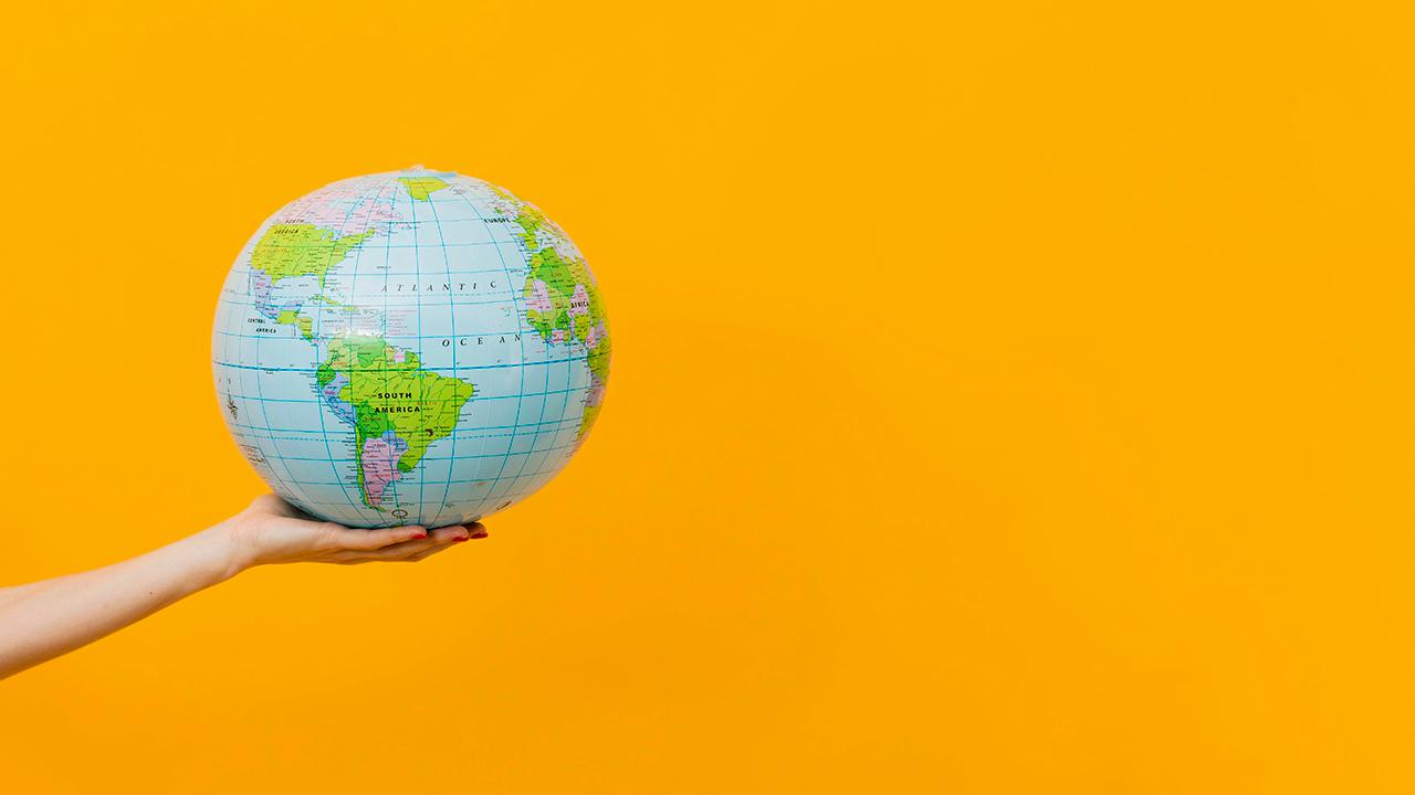 LiviTravel Travel Agency agent holding colorful world globe on vibrant yellow background symbolizing global care and unity.