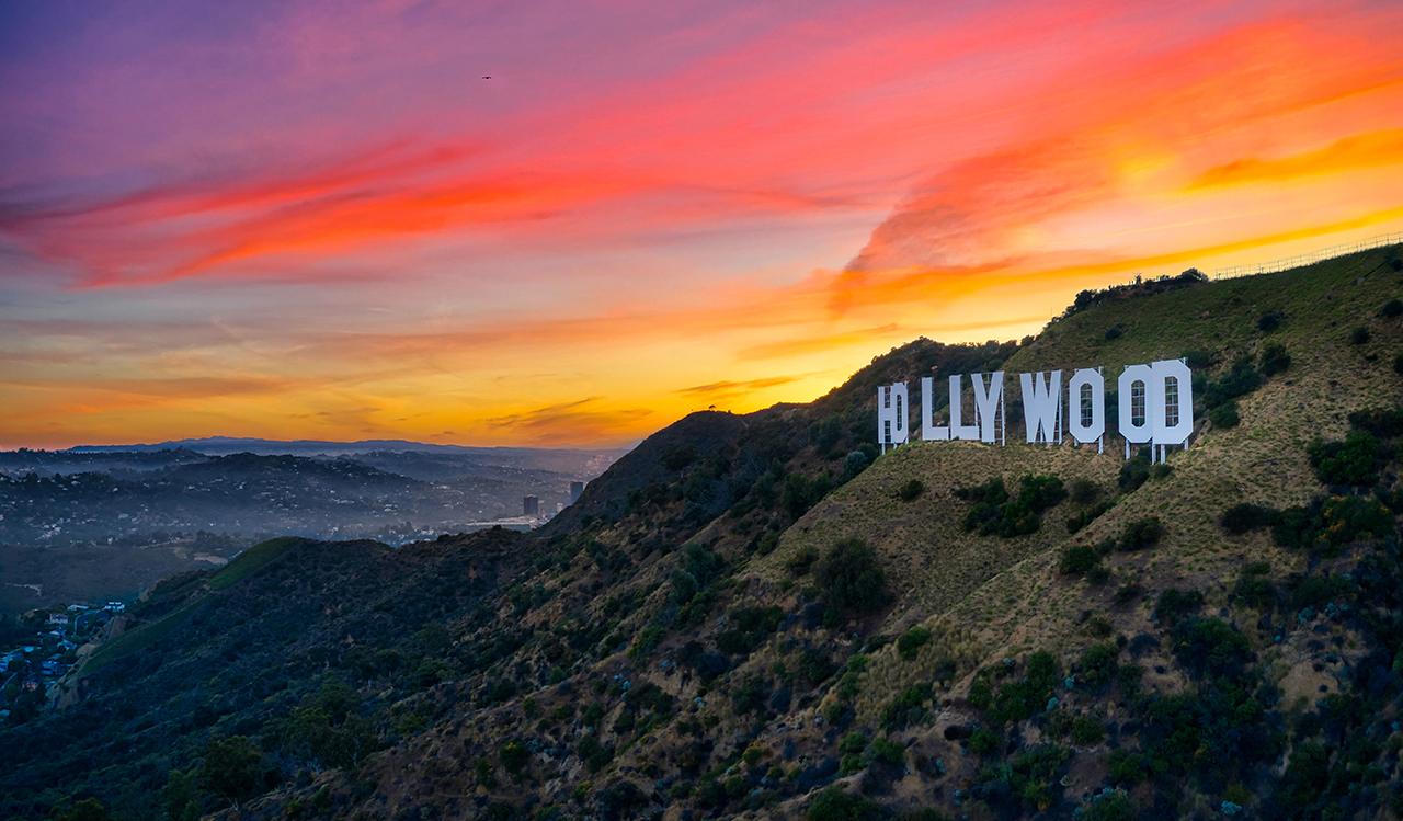 Hollywood Sign at sunset with colorful sky over Los Angeles hills and cityscape.
