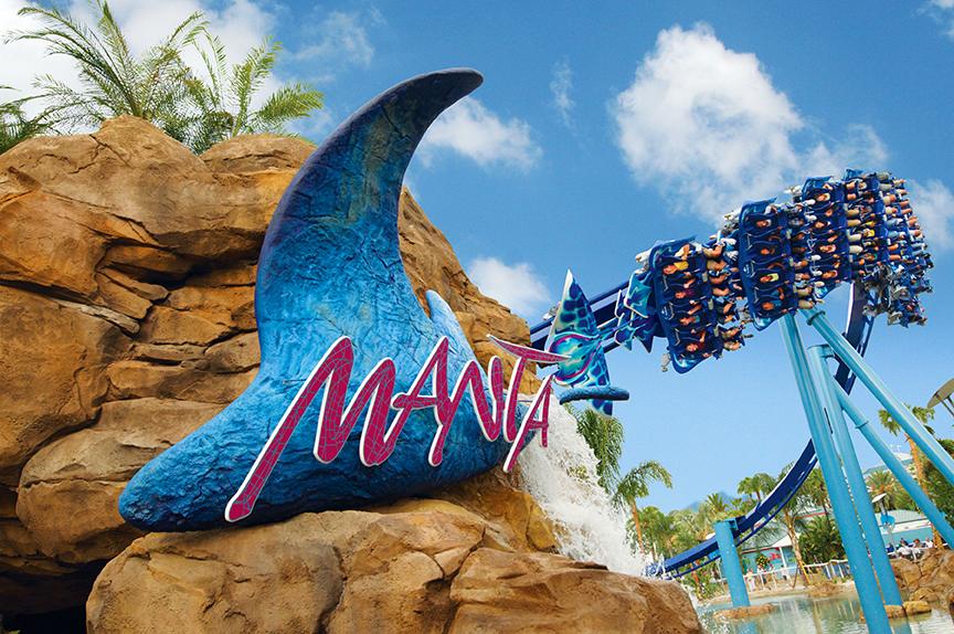 Manta roller coaster at SeaWorld Orlando with manta ray sign, riders, and tropical scenery.