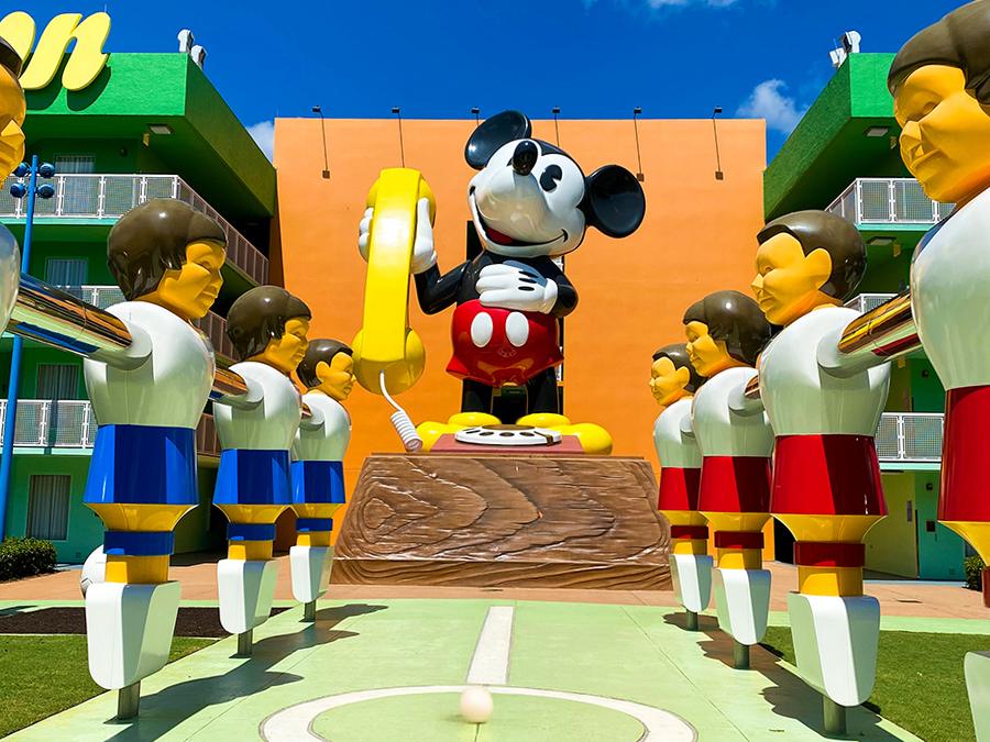 Giant Mickey Mouse statue with soccer players at Disney World Resort outdoor display.
