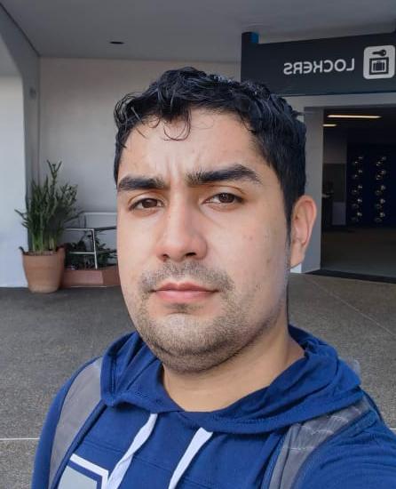 Young man in blue hoodie taking casual selfie with modern urban background.