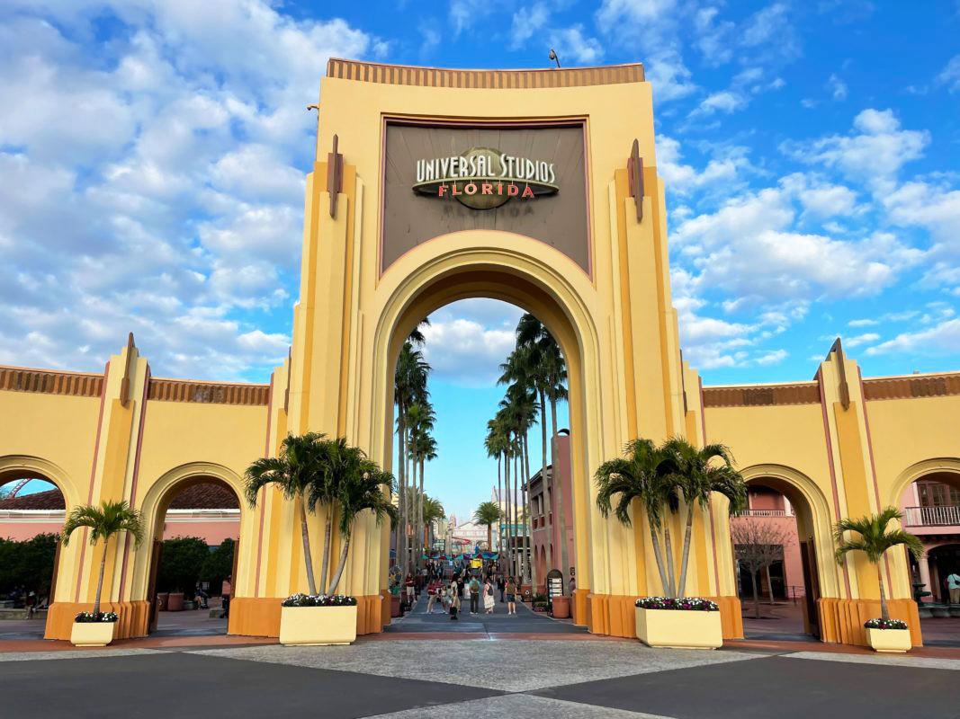 Universal Studios Florida entrance arch with palm trees under a bright blue sky.