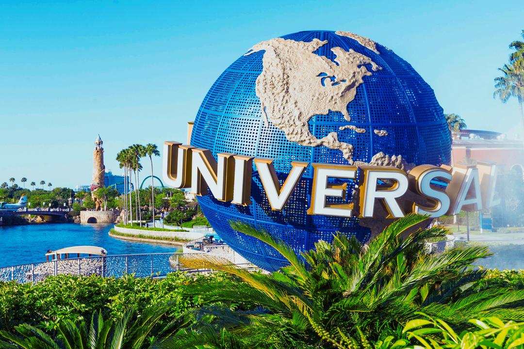 Universal Studios Orlando globe with palm trees and waterway at scenic park entrance