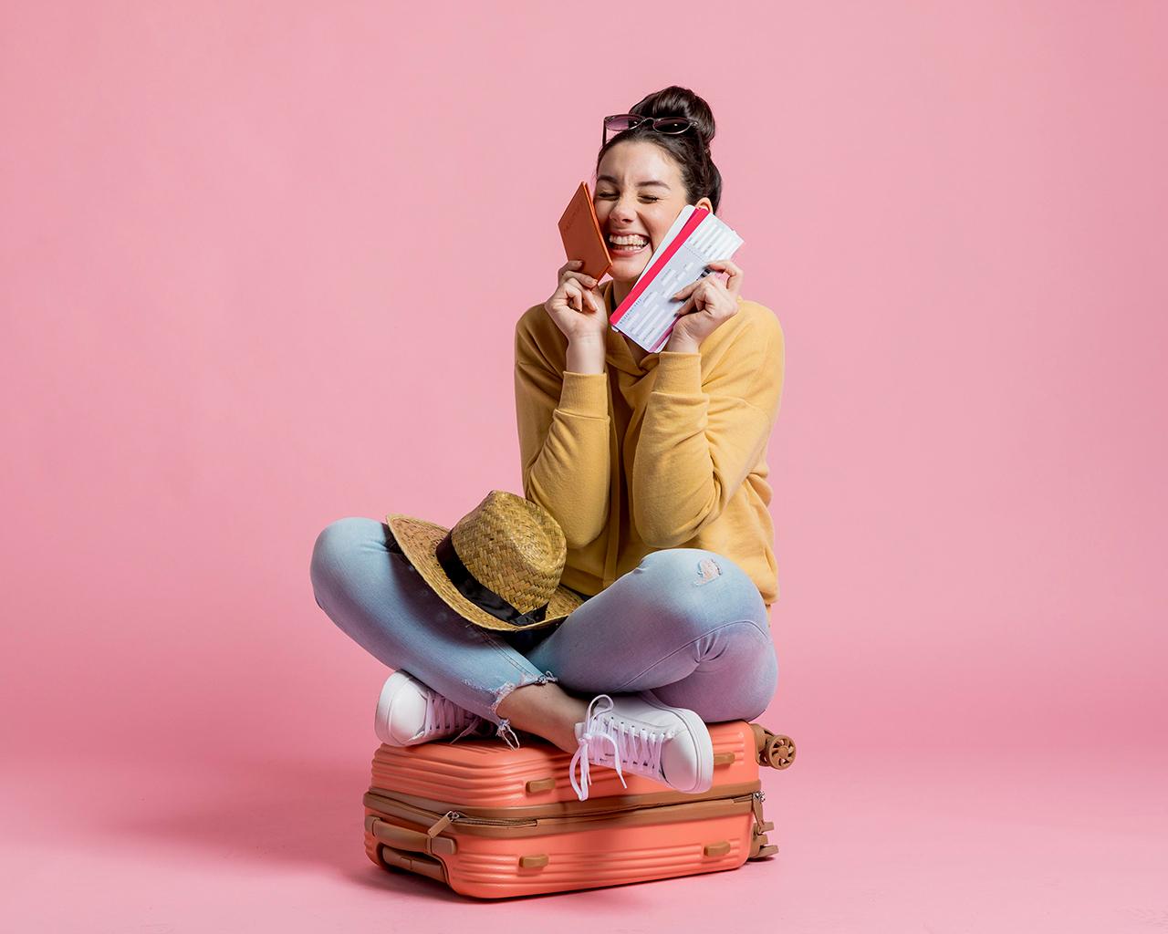 Smiling woman with suitcase, passport, and ticket ready for travel adventure.