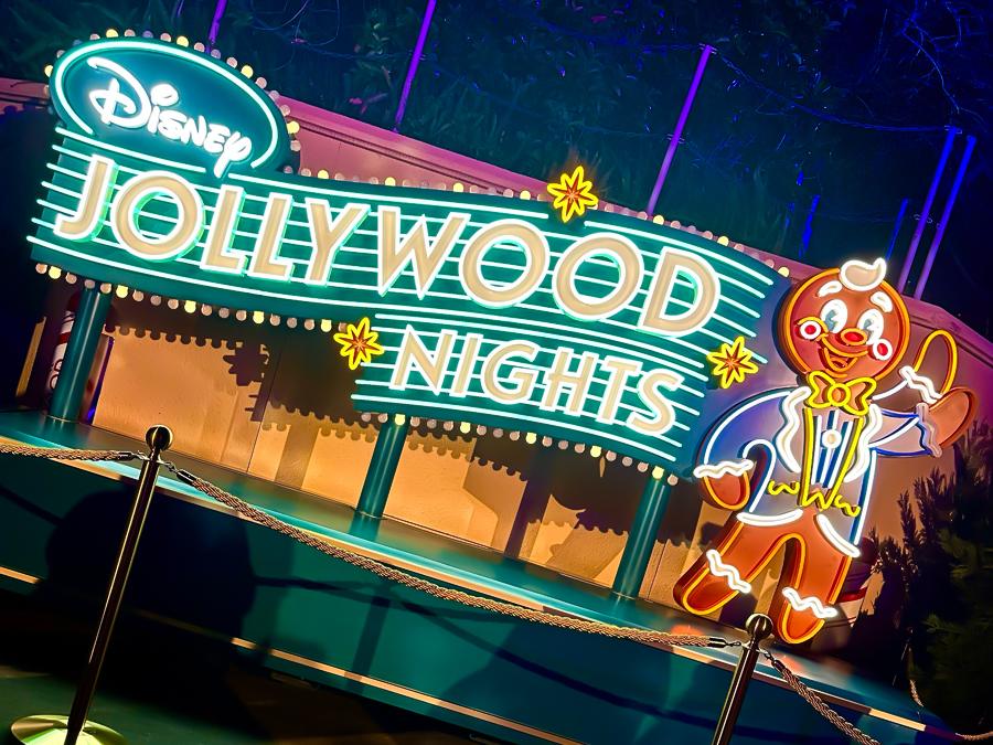 Disney Jollywood Nights neon sign with festive character at Hollywood Studios holiday event.