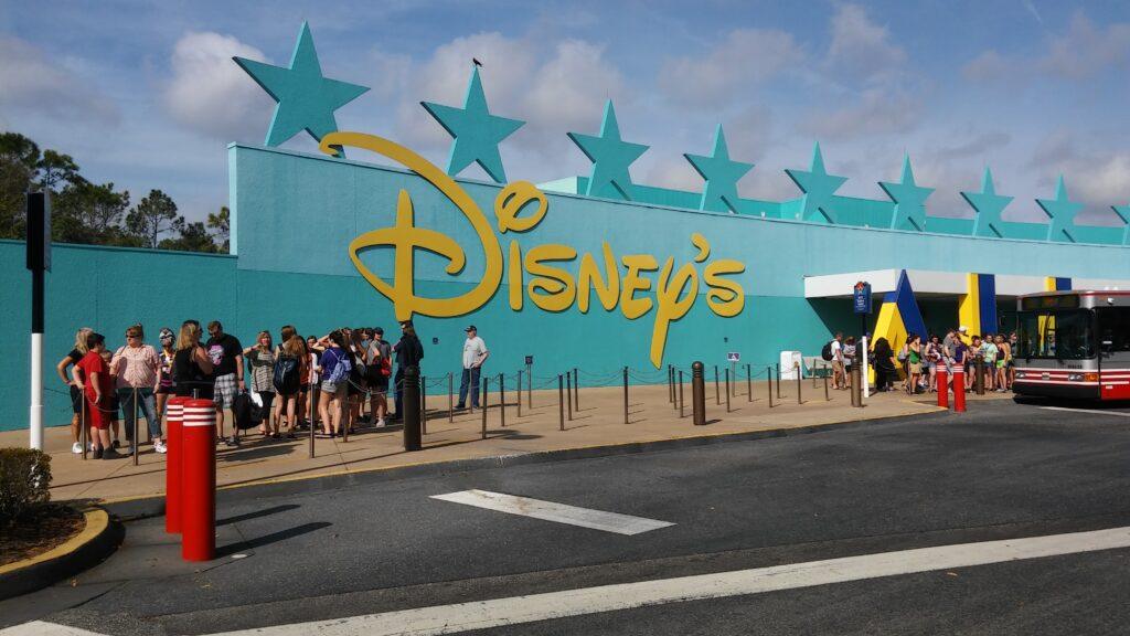 Entrada y parada de autobús en Disney’s All-Star Music Resort con fila de huéspedes; hoteles en Disney Orlando